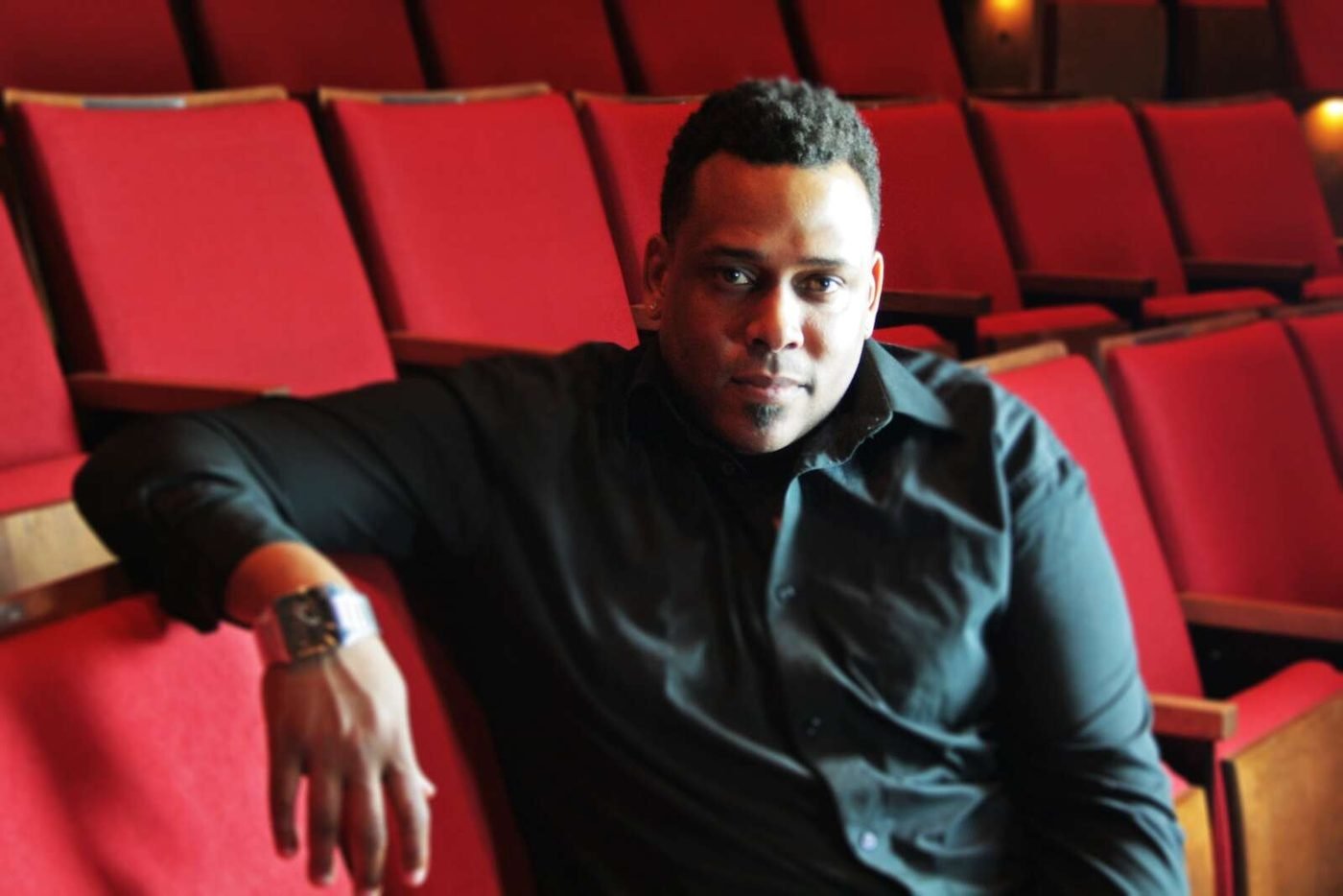 Daryl D. Brooks seated in the red seats of Black Ensemble Theater